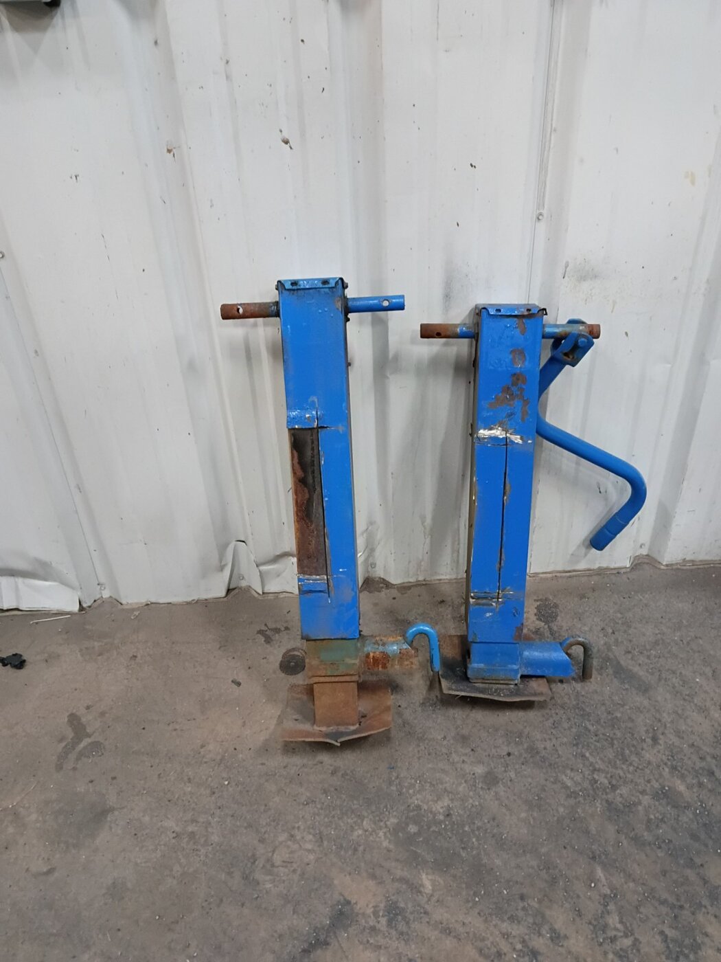 Two blue jack components standing against the workshop wall.