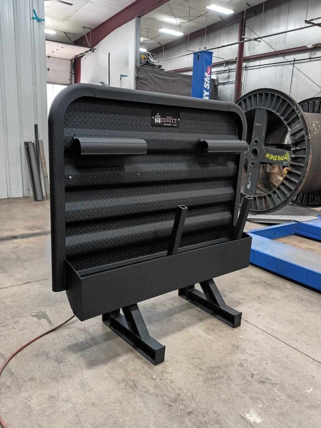 A black diamond-plate assembly on stands in the workshop.